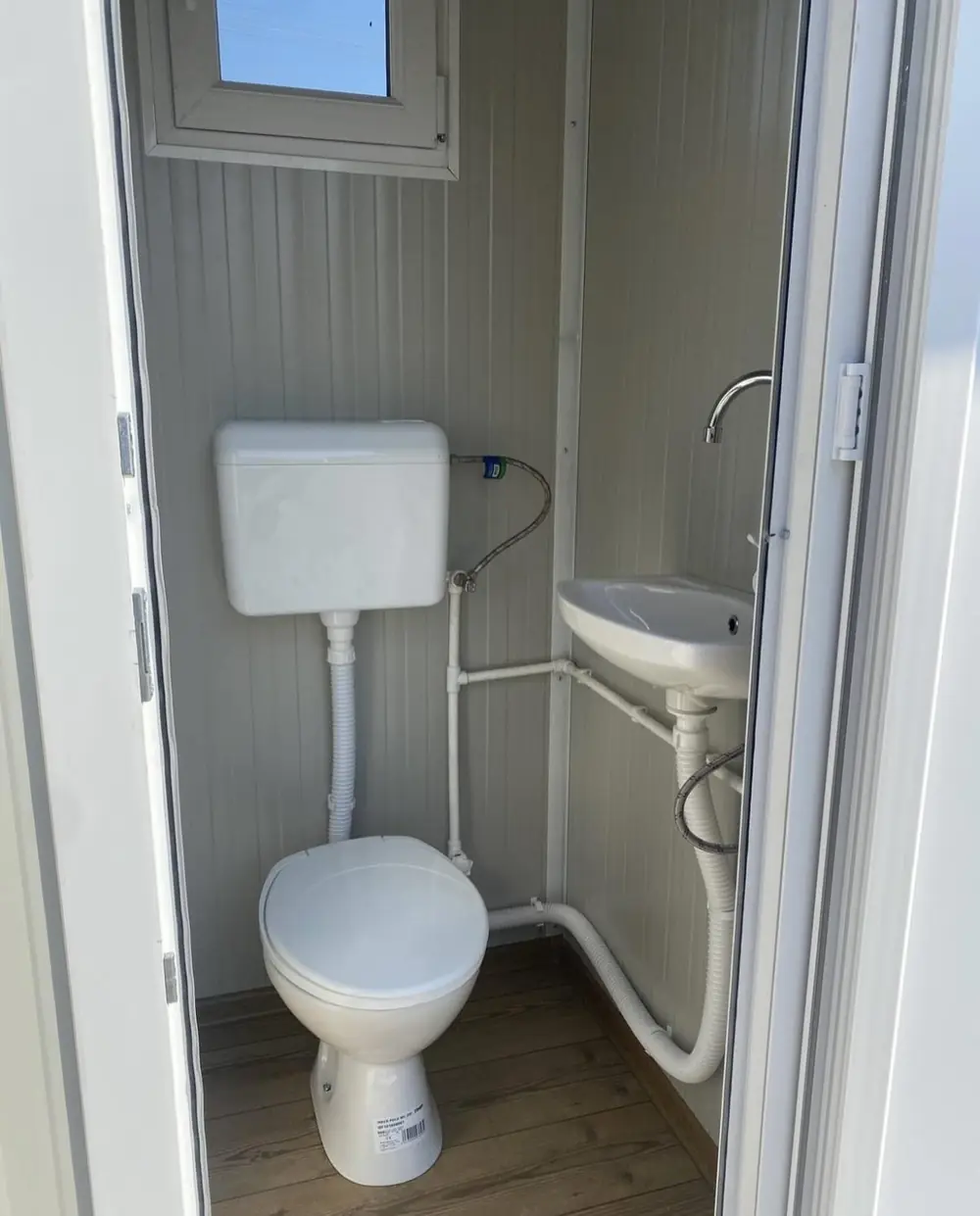 Inside a flushing restroom cabin with a white toilet and wall sink